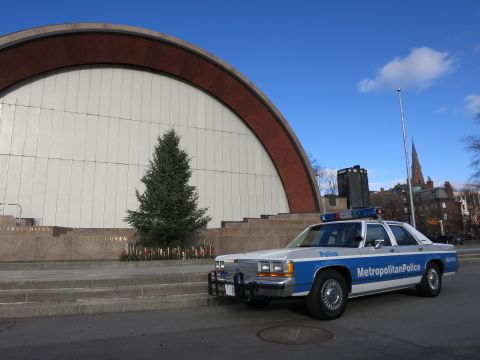1991 Ford LTD Crown Victoria - A police car is parked in front of a building with a large arched window and a Christmas tree.