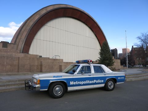1991 Ford LTD Crown Victoria - Photo of a Metropolitan Police Crown Victoria patrol car parked before an arched bandshell.