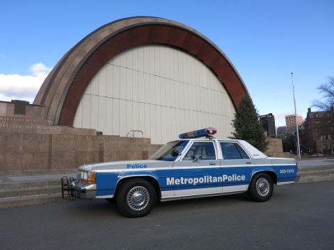 1991 Ford LTD Crown Victoria - Photo of a blue and white Metropolitan Police Crown Victoria parked at an arched bandshell.
