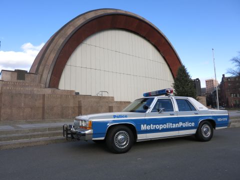 1991 Ford LTD Crown Victoria - Photo of a Metropolitan Police Ford LTD Crown Victoria cruiser parked before a curved bandshell, not a technical document.