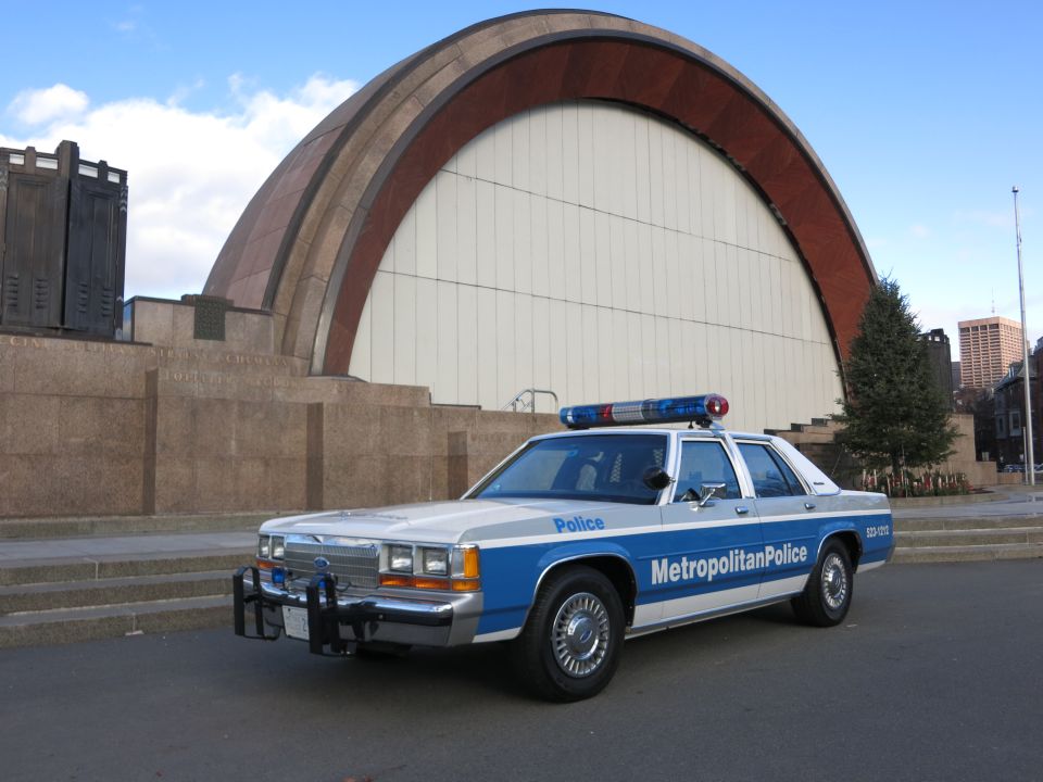 Metropolitan Police Crown Victoria cruiser at front quarter angle before a bandshell