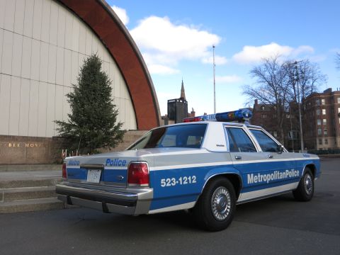1991 Ford LTD Crown Victoria - Photo of the rear of a Metro Police Crown Victoria cruiser parked near a bandshell, not a technical document.