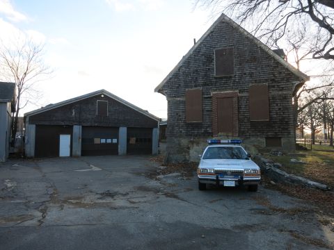1991 Ford LTD Crown Victoria - Photo of a police Crown Victoria cruiser parked in front of an abandoned house and barn, not a technical document.
