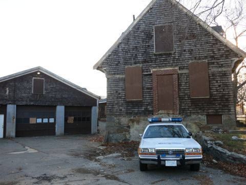 1991 Ford LTD Crown Victoria - Photo of the front of a police Crown Victoria cruiser parked at an abandoned shingled house, not a technical document.