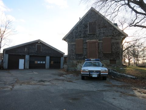 1991 Ford LTD Crown Victoria - Photo of a Metropolitan Police Crown Victoria cruiser parked before old garage bays, not a technical document.