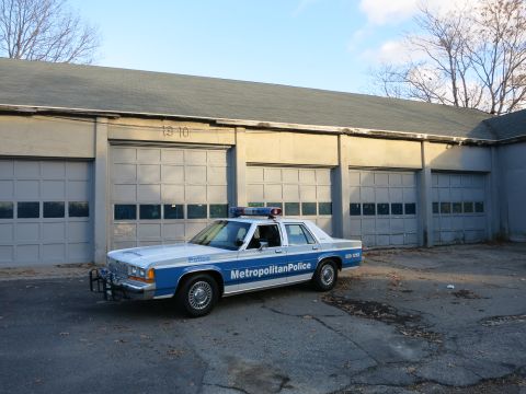 1991 Ford LTD Crown Victoria - Photo of a Metropolitan Police Crown Victoria cruiser before a row of garage doors, not a technical document.