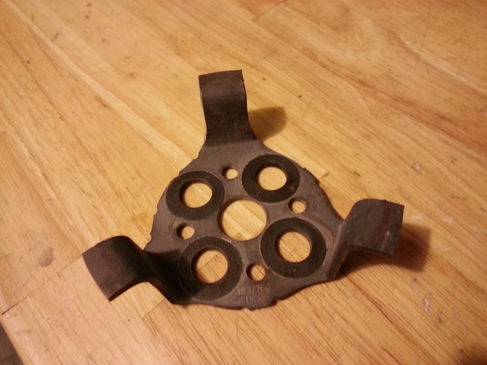 Dark metal part with circular cutouts and text "4031760 USA" on wood