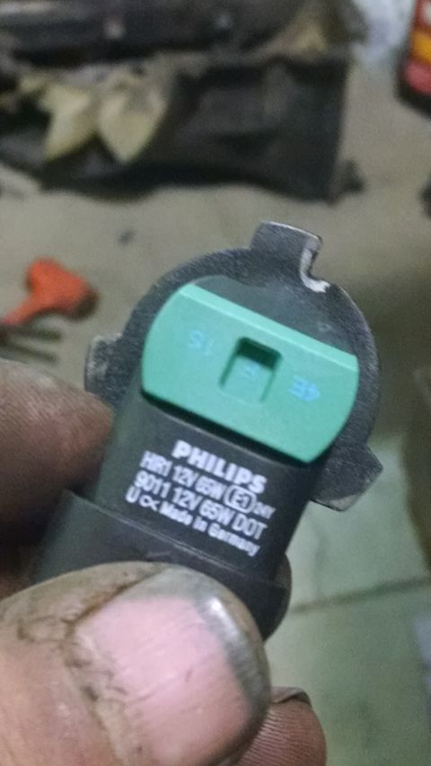 2000 Chevrolet Astro - A close-up shot shows a Philips HR1 12V 65W headlight bulb with "Made in Germany" printed on it. The bulb has a green plastic base with blu…