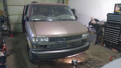 2000 Chevrolet Astro - The front view of a two-tone brown and maroon Chevrolet Astro van parked in a garage. The van has its hood open and appears to be undergoin…
