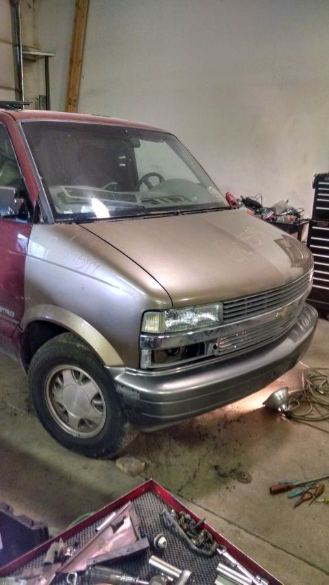 2000 Chevrolet Astro - A two-tone Chevrolet Astro van is shown in a garage setting. The front fender and hood are a light brown color, while the front door and re…