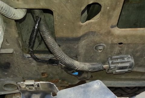 1994 Ford Bronco - Photograph of an automotive wiring harness and electrical connector behind a body panel.