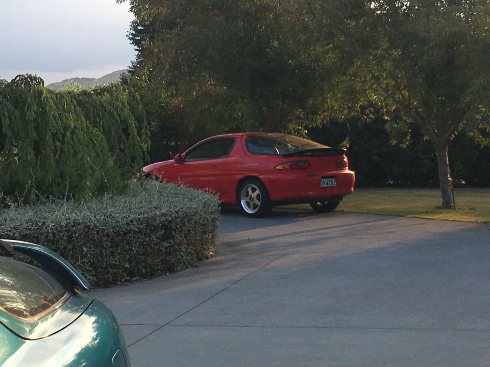 Red 1993 Mazda MX-3 parked in a driveway.