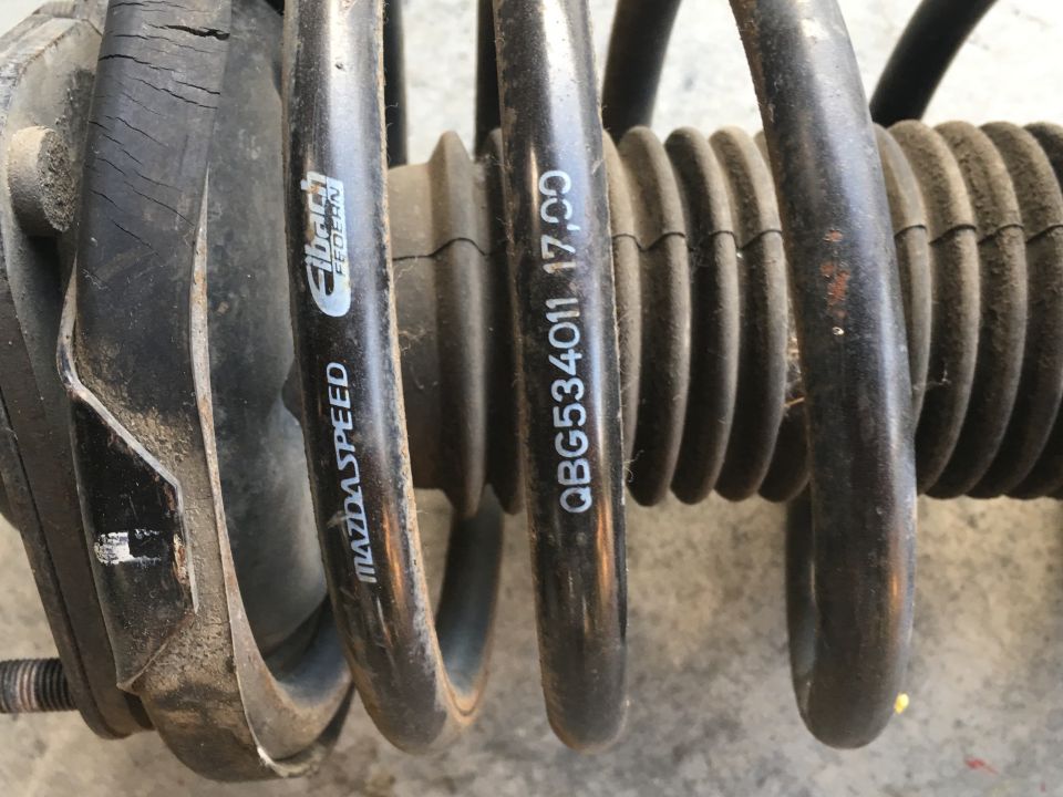 Close-up of a dusty black Eibach coilover spring with MAZDASPEED and part number text.