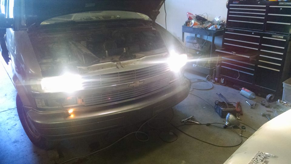 2000 Chevrolet Astro van front view, hood open, headlights on, in a garage.