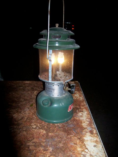 1982 Ford F-100 - A green Coleman lantern with two mantles is lit and sits on a rusty metal surface.