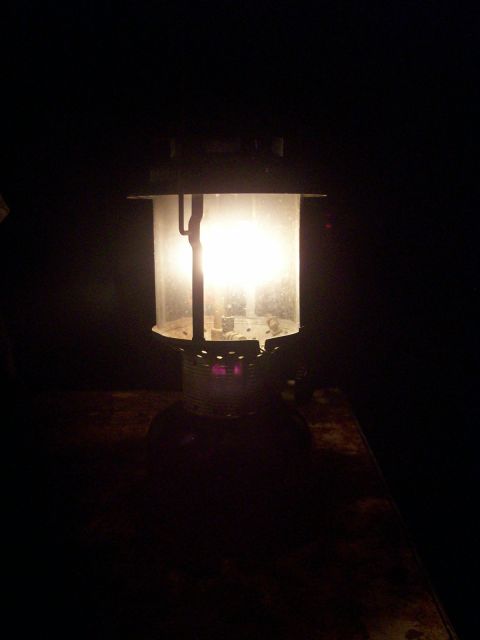 1982 Ford F-100 - A lit kerosene lantern sits on a dark, textured surface in a dimly lit environment.