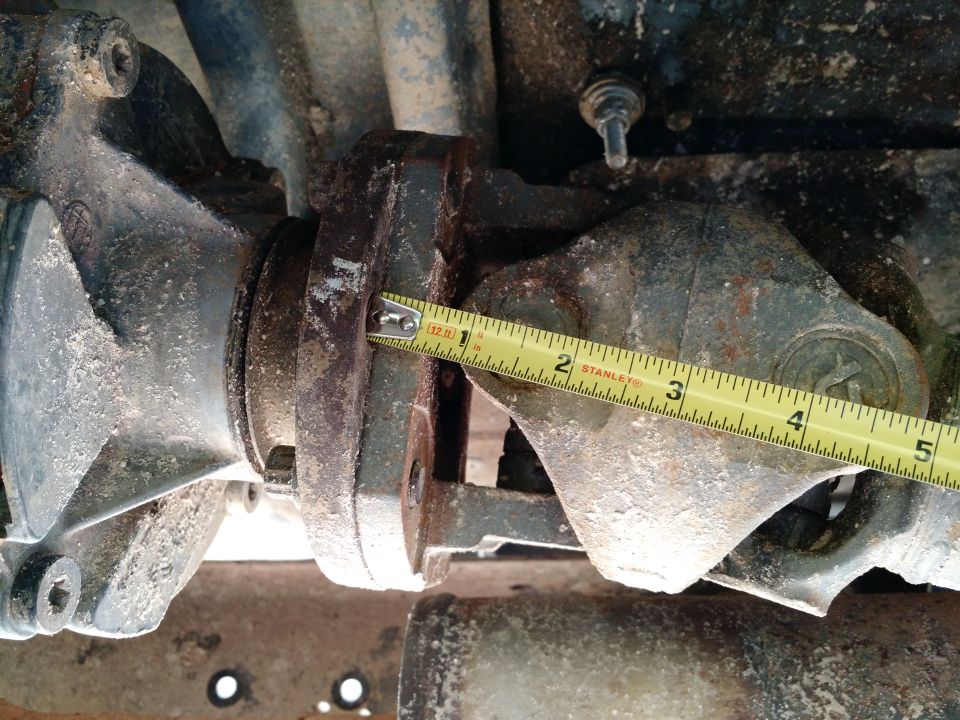 Close-up of a drive shaft flange being measured with a yellow Stanley tape measure.