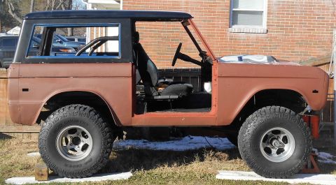 1972 Ford Bronco - The side profile of a vintage Ford Bronco undergoing restoration. The vehicle is painted in a reddish-brown primer and features a black har…