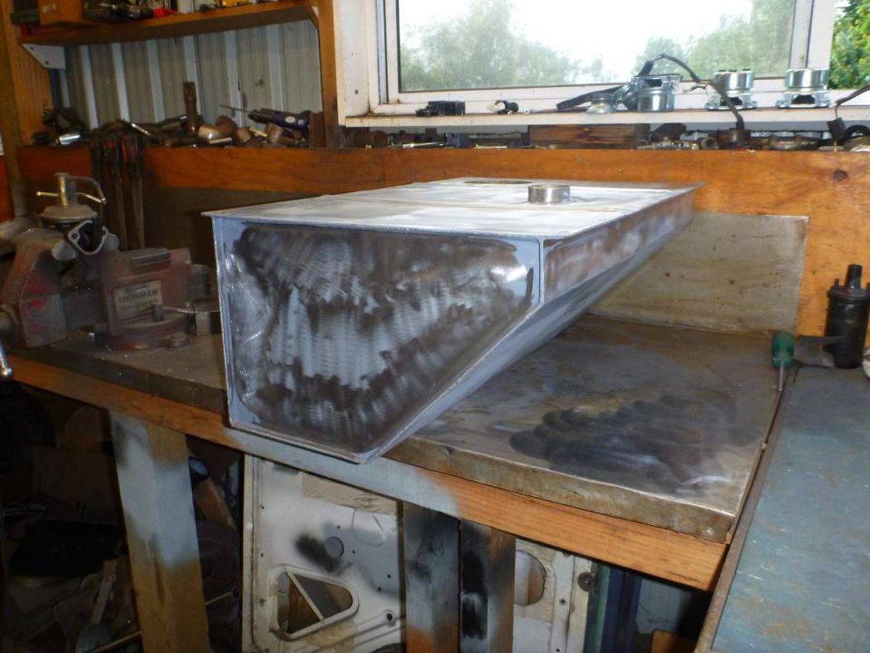 Raw metal custom fuel tank on a workbench