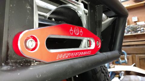 1967 Ford F-250 - Close-up of a red tow hook with "POLYPERFORMANCE" branding and humorous graphics, attached to a vehicle's bumper.
