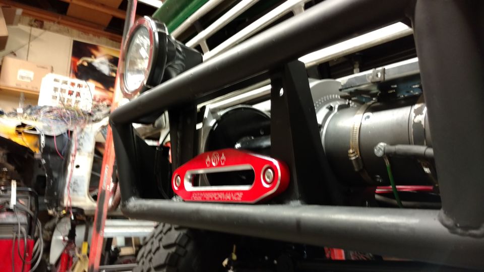 Red winch fairlead with text 'PERFORMANCE' mounted on a black bull bar. A headlight is visible above