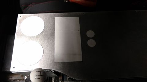 1967 Ford F-250 - Interior view of a metal panel with circular cutouts and a taped section, next to a gear shift knob.