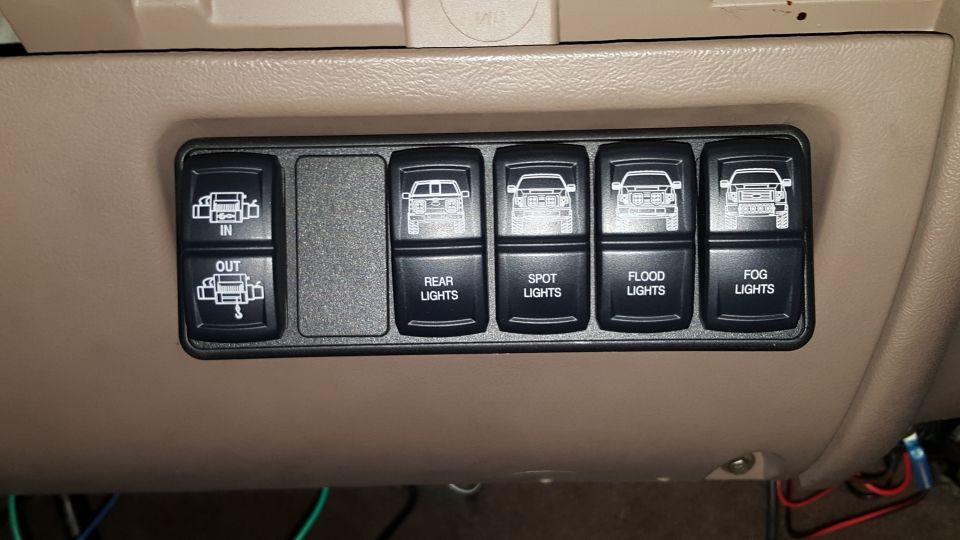 Aftermarket rocker switch panel with winch in/out and rear, spot, flood, fog light switches