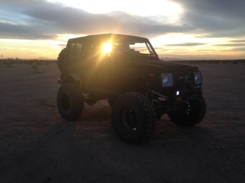 1987 Suzuki Samurai - Modified 1987 Suzuki Samurai with off-road tires in a desert setting during sunset.