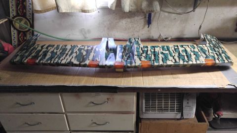 1991 Ford Bronco - A camouflage-painted truck sun visor with integrated orange marker lights is displayed on a table.