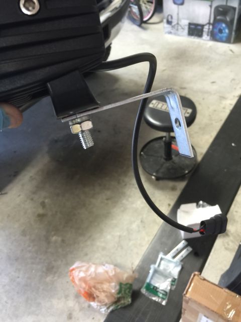 1996 Ford Bronco - A person is installing a fog light onto a vehicle, showing the mounting hardware and wiring.