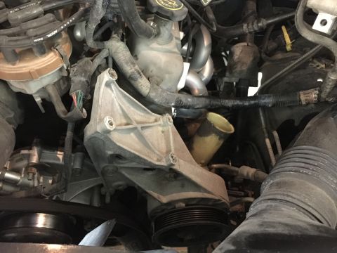 1996 Ford Bronco - Close-up view of engine components, including a bracket, pulley, and hoses.