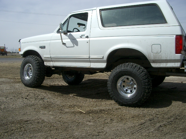 White Ford Bronco SUV with lifted suspension and large tires, viewed from the side