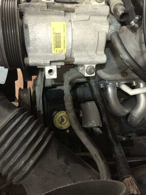 1996 Ford Bronco - Close-up of an AC compressor unit within an engine bay, showing hoses and belts.