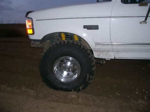 1994 Ford Bronco - Front quarter view of a white 1994 Ford Bronco, showing the fender, wheel, and "BRONCO" badging.