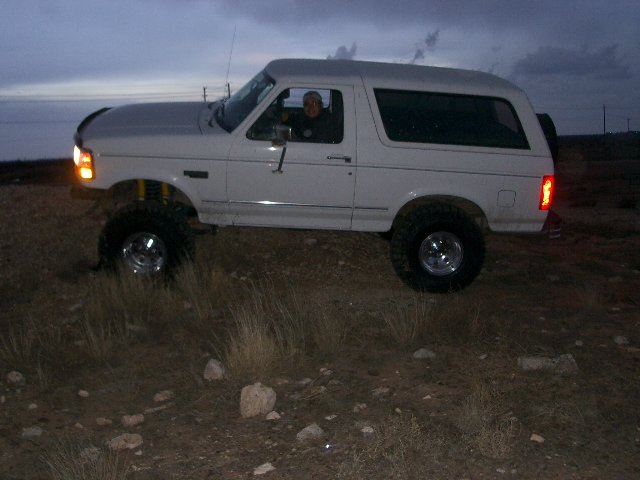 White Ford Bronco with lifted suspension and off-road tires, viewed from the front-right