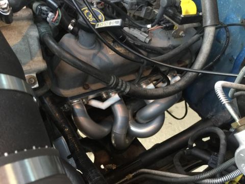1996 Ford Bronco - Close-up view of an engine bay, focusing on the exhaust manifold and various hoses and wiring.