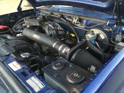1996 Ford Bronco - The engine bay of a blue vehicle features an aftermarket K&N air intake system.