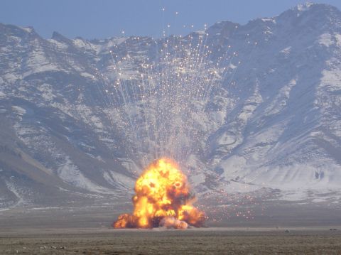 1981 Ford Bronco - A massive explosion sends fire and debris into the sky against a backdrop of snow-dusted mountains.