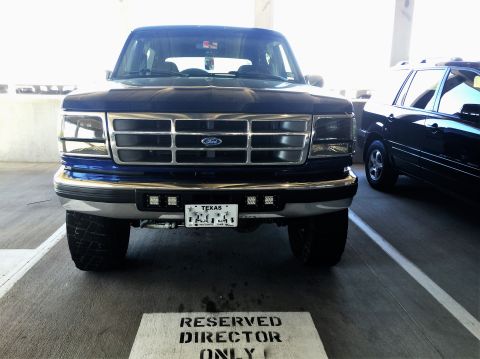 1996 Ford Bronco - Front view of a blue Ford Bronco with a chrome grille and Texas license plate, parked in a garage.