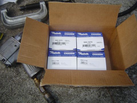 1986 Ford Bronco - Raybestos chassis parts and automotive tools are laid out on a concrete surface.