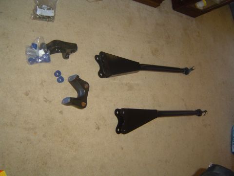 1986 Ford Bronco - Automotive suspension components are laid out on a carpeted surface, including arms and mounting brackets.