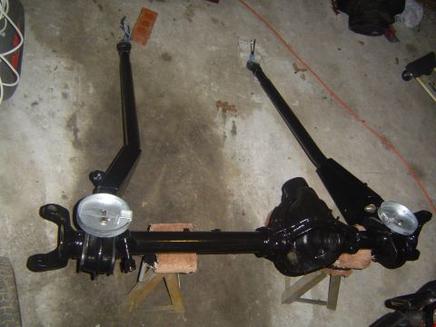 1986 Ford Bronco - A black front axle assembly, likely for an off-road vehicle, is shown disassembled and resting on blocks.
