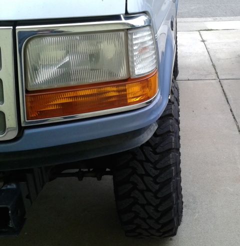 1996 Ford Bronco - Close-up of the front right tire and fender of a light blue 1996 Ford Bronco.