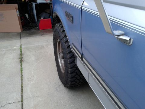 1996 Ford Bronco - Close-up side view of a blue 1996 Ford Bronco, highlighting its aggressive tires and classic body lines.