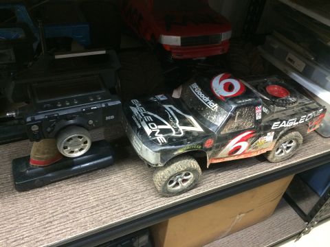 1989 Ford Bronco - Remote control truck and controller on a shelf, with another red vehicle in the background.