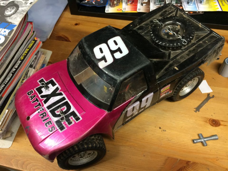 Pink and black toy RC truck with "EXIDE BATTERIES" and "99" graphics