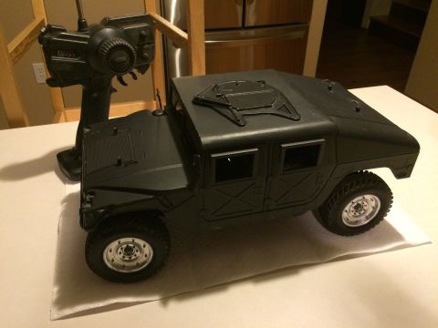 1989 Ford Bronco - A black remote control vehicle sits on a surface next to its controller, with a kitchen in the background.