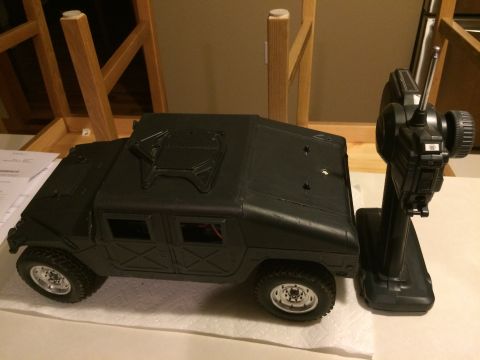 1989 Ford Bronco - A black remote control toy truck sits next to its controller on a white surface.