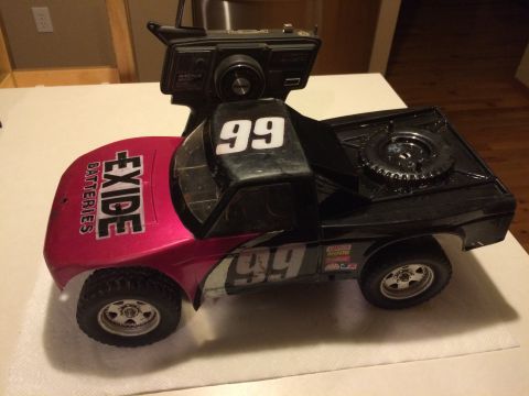 1989 Ford Bronco - This remote control truck features a pink front fender and door with 'Exide Batteries' branding, and a black rear with '99' racing numbers.