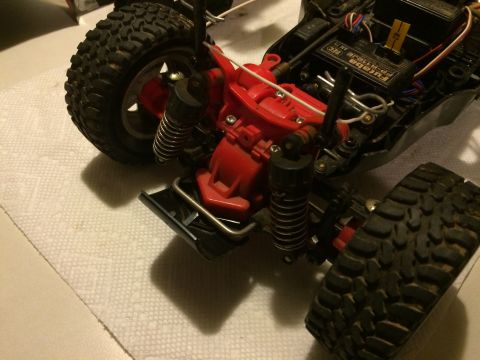 1989 Ford Bronco - Close-up view of the rear suspension and drivetrain of a remote-controlled off-road vehicle. The red plastic gearbox housing and black shoc…